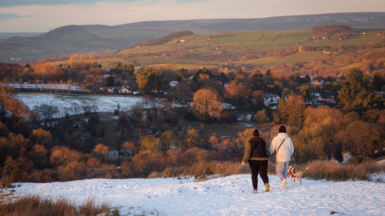 Visitors walking in the parkland at sunset surrounded by an autumnal snow-covered landscape